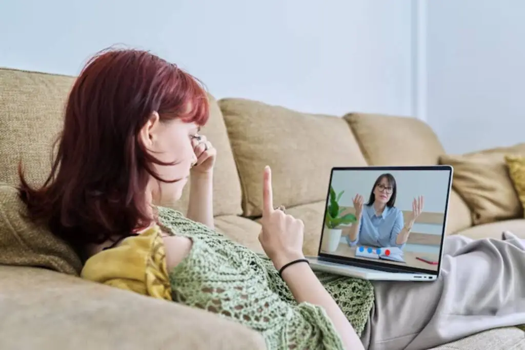 A woman attending an online meeting on her laptop for Telepsychiatry Care services