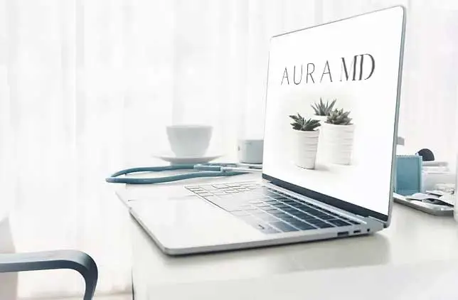 A laptop placed on a table with Aura MD screen open on it