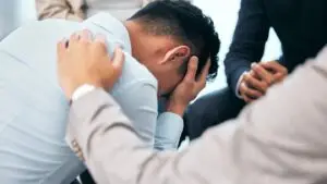 Stressed man comforted by group support members